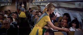 Movie still from “Airport” (1970), directed by George Seaton – A woman in a yellow dress standing on an airplane; Medium shot, Low angle