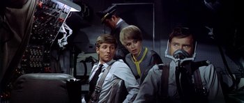 Movie still from “Airport” (1970), directed by George Seaton – A man and a woman sitting next to each other on a plane; Medium shot, Low angle