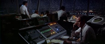 Movie still from “Airport” (1970), directed by George Seaton – A control room with a lot of people in the background; Medium shot, High angle