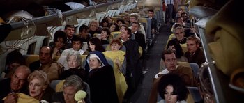 Movie still from “Airport” (1970), directed by George Seaton – A large group of people sitting on a plane; Wide shot, High angle
