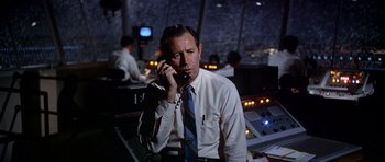 Movie still from “Airport” (1970), directed by George Seaton – A man talking on a phone while sitting in an airplane; Medium shot, Low angle