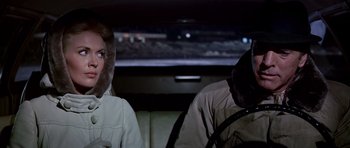 Movie still from “Airport” (1970), directed by George Seaton – A man and a woman sitting in the back of a car; Medium shot, Over the shoulder angle