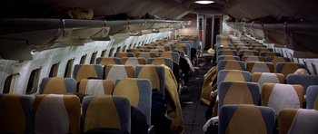 Movie still from “Airport” (1970), directed by George Seaton – Rows of seats in an airplane with blankets on the seats; Wide shot, High angle