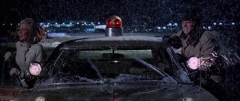 Movie still from “Airport” (1970), directed by George Seaton – A police car with its lights turned on at night in the rain; Wide shot, Low angle