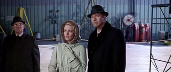 Movie still from “Airport” (1970), directed by George Seaton – A man and a woman standing next to each other in front of a building; Medium shot, Low angle