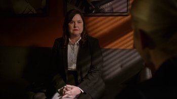 Movie still from “Better Call Saul” (2015), created by Vince Gilligan – A woman sitting on a couch in front of a picture; Medium shot, Over the shoulder angle