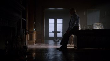 Movie still from “Better Call Saul” (2015), created by Vince Gilligan – A man sitting on a chair in a dark room; Wide shot, Low angle