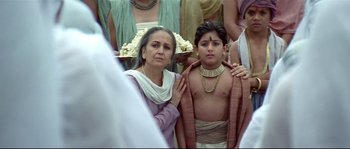 Movie still from “Asoka” (2001), directed by Santosh Sivan – A woman and a young boy are standing together; Medium shot, Low angle