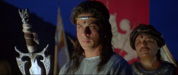 Movie still from “Asoka” (2001), directed by Santosh Sivan – A man with long black hair wearing a headband; Close Up shot, High angle