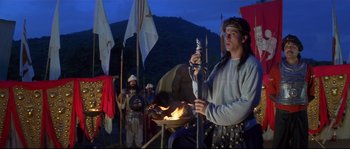 Movie still from “Asoka” (2001), directed by Santosh Sivan – A group of people standing next to a fire pit; Wide shot, Low angle