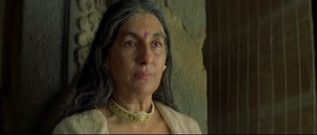 Movie still from “Asoka” (2001), directed by Santosh Sivan – An older woman with long grey hair wearing a necklace; Close Up shot, Low angle