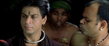 Movie still from “Asoka” (2001), directed by Santosh Sivan – A man with a green head scarf and a man with a white beard and nose ring; Close Up shot, Over the shoulder angle