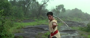 Movie still from “Asoka” (2001), directed by Santosh Sivan – A man holding a sword in his hands; Medium shot, Low angle