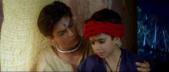 Movie still from “Asoka” (2001), directed by Santosh Sivan – A man and a boy are sitting next to each other; Close Up shot, High angle