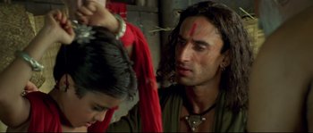 A man with long dark hair is looking at a woman with long dark hair