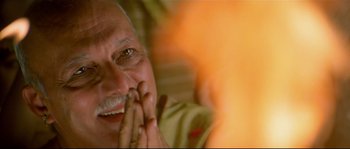 Movie still from “Asoka” (2001), directed by Santosh Sivan – An older man with his hands clasped in front of his face; Close Up shot, High angle
