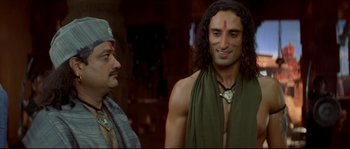 Movie still from “Asoka” (2001), directed by Santosh Sivan – A man in a green shirt is standing next to another man in a green shirt; Medium shot, Low angle