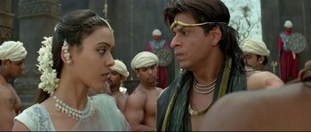 Movie still from “Asoka” (2001), directed by Santosh Sivan – A man and a woman are standing in front of other men; Close Up shot, Over the shoulder angle