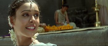 Movie still from “Asoka” (2001), directed by Santosh Sivan – A woman in a white dress is smiling at the camera; Close Up shot, Low angle