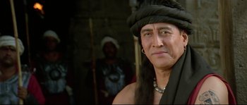 Movie still from “Asoka” (2001), directed by Santosh Sivan – A man in a black hat and a black shirt; Close Up shot, Low angle