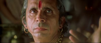 Movie still from “Asoka” (2001), directed by Santosh Sivan – An older man with a red head covering; Extreme Close Up shot, Low angle