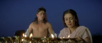 Movie still from “Asoka” (2001), directed by Santosh Sivan – A man and a woman sitting in front of lit candles; Medium shot, High angle