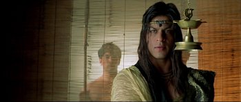 Movie still from “Asoka” (2001), directed by Santosh Sivan – A man with long black hair wearing a yellow shirt; Close Up shot, Over the shoulder angle