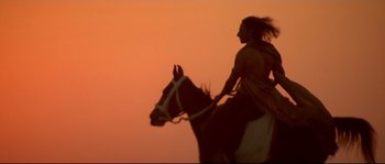 Movie still from “Asoka” (2001), directed by Santosh Sivan – A man riding a horse at sunset with the sky in the background; Wide shot, Low angle