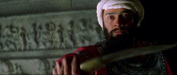 Movie still from “Asoka” (2001), directed by Santosh Sivan – A man with a beard holding a baseball bat in his hands; Close Up shot, Low angle