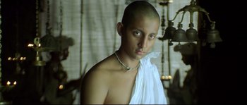 Movie still from “Asoka” (2001), directed by Santosh Sivan – A young man wearing a white shirt and a necklace; Close Up shot, Low angle
