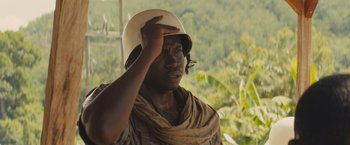 Movie still from “Beasts of No Nation” (2015), directed by Cary Joji Fukunaga – A man wearing a white hat and a scarf; Close Up shot, Over the shoulder angle