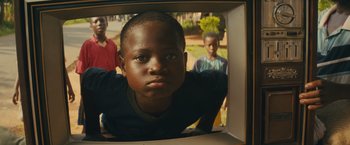 Movie still from “Beasts of No Nation” (2015), directed by Cary Joji Fukunaga – A young boy is looking into a box; Close Up shot, Over the shoulder angle