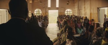 Movie still from “Beasts of No Nation” (2015), directed by Cary Joji Fukunaga – A large group of people sitting in a room; Extreme Wide shot, High angle
