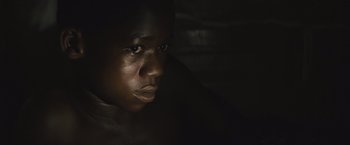 Movie still from “Beasts of No Nation” (2015), directed by Cary Joji Fukunaga – A young man is looking into the camera; Close Up shot, High angle