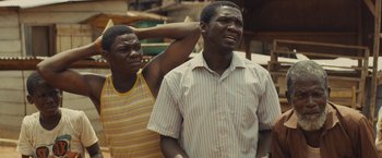 Movie still from “Beasts of No Nation” (2015), directed by Cary Joji Fukunaga – Two men standing next to each other and one of the men has his hand on his shoulder; Close Up shot, Low angle