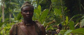 Movie still from “Beasts of No Nation” (2015), directed by Cary Joji Fukunaga – A man in a military uniform standing in front of trees; Close Up shot, Low angle