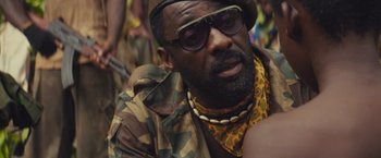 Movie still from “Beasts of No Nation” (2015), directed by Cary Joji Fukunaga – A person wearing a hat and sunglasses; Close Up shot, Over the shoulder angle