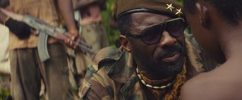 Movie still from “Beasts of No Nation” (2015), directed by Cary Joji Fukunaga – A man in a military uniform with sunglasses on; Close Up shot, Low angle