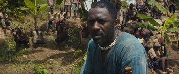 Movie still from “Beasts of No Nation” (2015), directed by Cary Joji Fukunaga – A man in a blue shirt is looking into the camera; Close Up shot, Over the shoulder angle