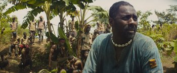 Movie still from “Beasts of No Nation” (2015), directed by Cary Joji Fukunaga – A group of people sitting in the grass; Close Up shot, Over the shoulder angle