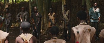 Movie still from “Beasts of No Nation” (2015), directed by Cary Joji Fukunaga – A group of men standing in the woods holding guns; Medium shot, Over the shoulder angle