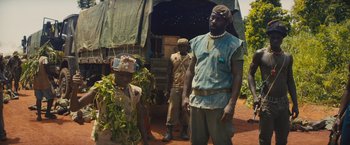 Movie still from “Beasts of No Nation” (2015), directed by Cary Joji Fukunaga – A group of men standing next to each other on a dirt ground; Medium shot, Low angle