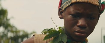 Movie still from “Beasts of No Nation” (2015), directed by Cary Joji Fukunaga – A person with a plant in their mouth; Close Up shot, Low angle