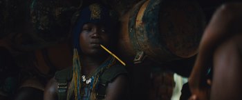 Movie still from “Beasts of No Nation” (2015), directed by Cary Joji Fukunaga – A person with a blue hat is smoking a cigarette; Close Up shot, Low angle