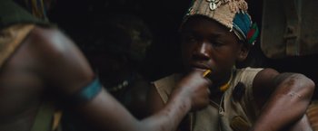 Movie still from “Beasts of No Nation” (2015), directed by Cary Joji Fukunaga – A man is holding a pencil in his mouth; Close Up shot, High angle