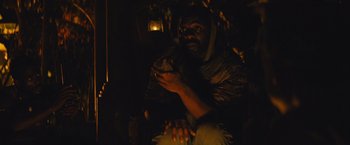 Movie still from “Beasts of No Nation” (2015), directed by Cary Joji Fukunaga – A man sitting in a dark room holding a cell phone; Medium shot, High angle