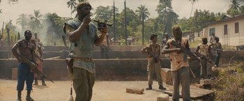Movie still from “Beasts of No Nation” (2015), directed by Cary Joji Fukunaga – A group of men standing next to each other on a dirt field; Medium shot, Low angle