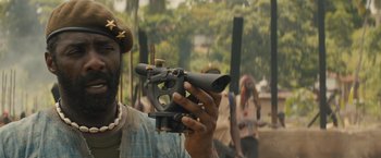 Movie still from “Beasts of No Nation” (2015), directed by Cary Joji Fukunaga – A man that is holding a gun; Close Up shot, Over the shoulder angle