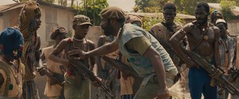 Movie still from “Beasts of No Nation” (2015), directed by Cary Joji Fukunaga – A group of men standing next to each other holding guns; Medium shot, Over the shoulder angle