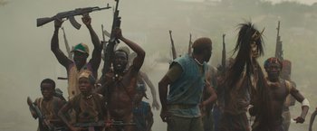 Movie still from “Beasts of No Nation” (2015), directed by Cary Joji Fukunaga – A group of men holding guns in the middle of a street; Medium shot, High angle